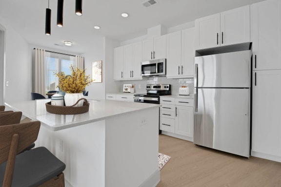 a white kitchen with a large island and stainless steel refrigerator at Metropolitan at the Riverwalk, Wilmington, NC