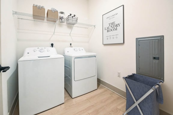 a washer and dryer in a laundry room with a shelf and a door at Metropolitan at the Riverwalk, Wilmington, NC