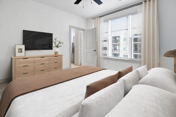 a white bedroom with a large bed and a tv at Metropolitan at the Riverwalk, Wilmington, NC