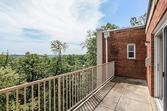 A balcony with a metal railing overlooks a lush green landscape.