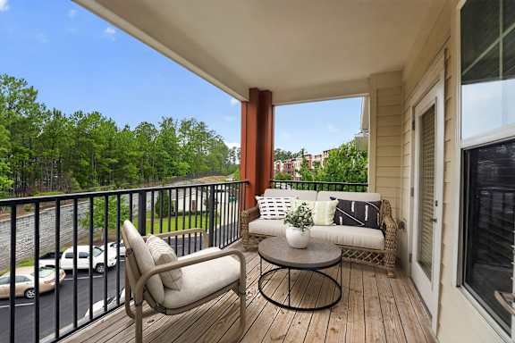 A balcony with a chair, a table, and a potted plant.