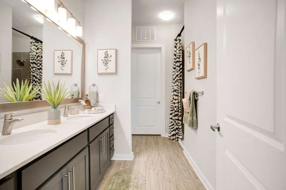 A bathroom with a white door and a mirror above the sink.