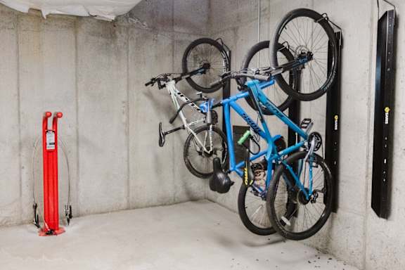 A blue bicycle is hanging on a wall in a garage.