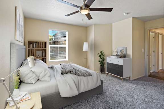A bedroom with a bed, nightstand, and a ceiling fan. at Bluffs Apartments, Bluffdale, UT, 84065