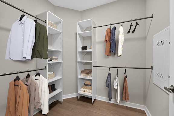 A white closet with clothes hanging and shelves.