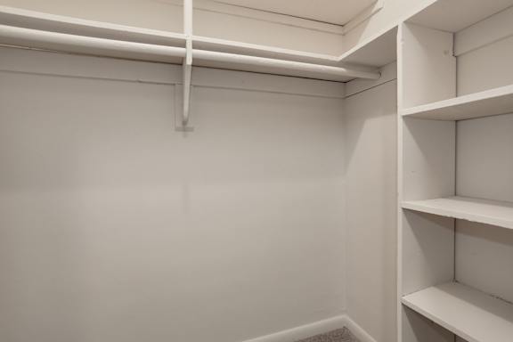 A white closet with a shelf and a hanging rod.