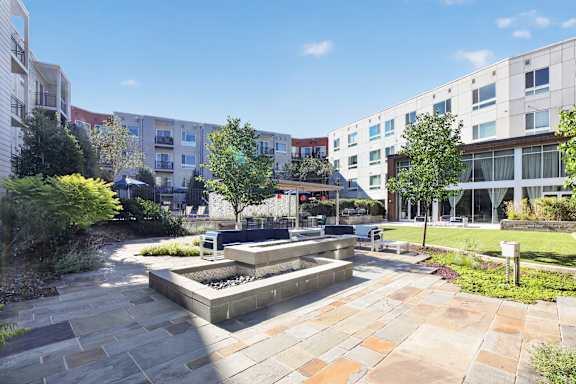 A sunny day in a courtyard with a fountain and a bench.