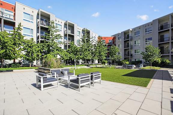 A sunny day at a modern apartment complex with a seating area in the foreground.