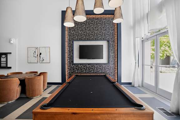 A pool table is in the middle of a room with a television and a fireplace.