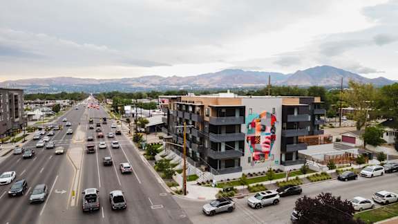 A busy street with cars and a large building with a mural on the side.