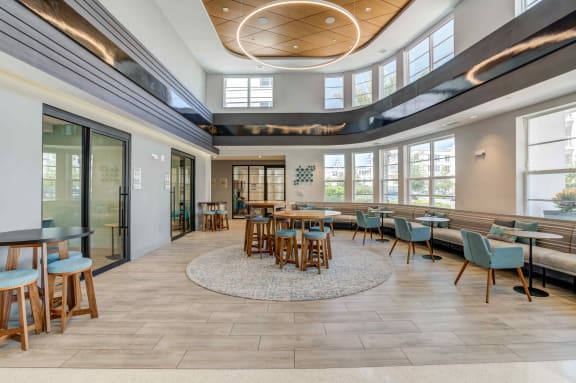 a common area with tables and chairs and a wall of windows at Delamarre at Celebration, Celebration