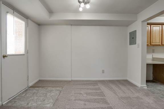 A room with a carpeted floor and a door on the left side.