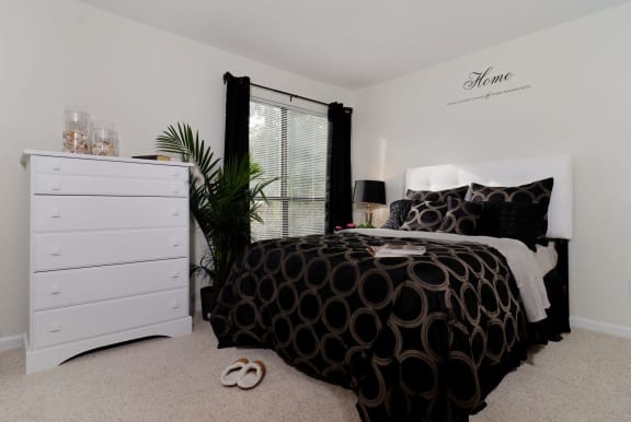 a bedroom with a bed with black and white bedding and a white dresser with a at Brampton Moors, North Carolina