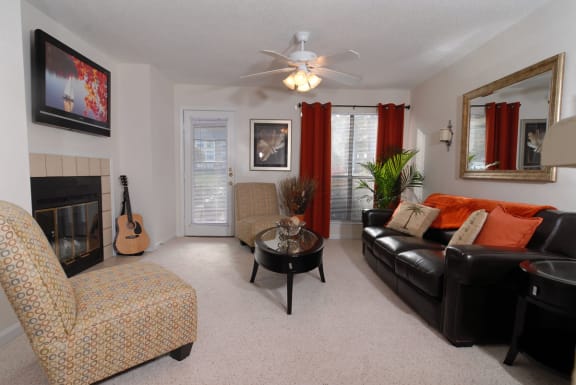 a living room with a fireplace and a ceiling fan at Brampton Moors, Cary, 27513