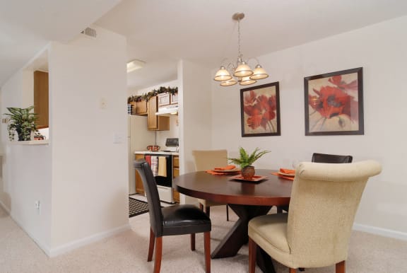 a dining area with a table and chairs and a kitchen in the background at Brampton Moors, Cary, NC, 27513