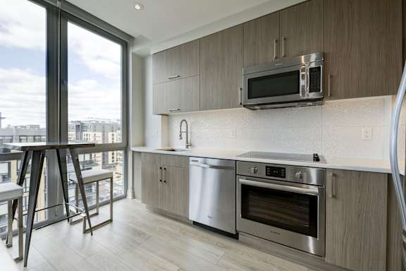 A modern kitchen with stainless steel appliances and a large window overlooking the city.