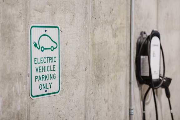 An electric vehicle parking sign is on a wall.