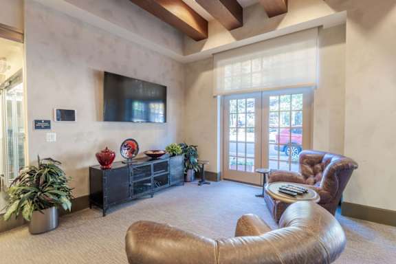 A living room with a brown leather chair and a flat screen TV mounted on the wall