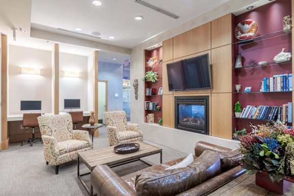A living room with a brown leather couch and a television on the wall