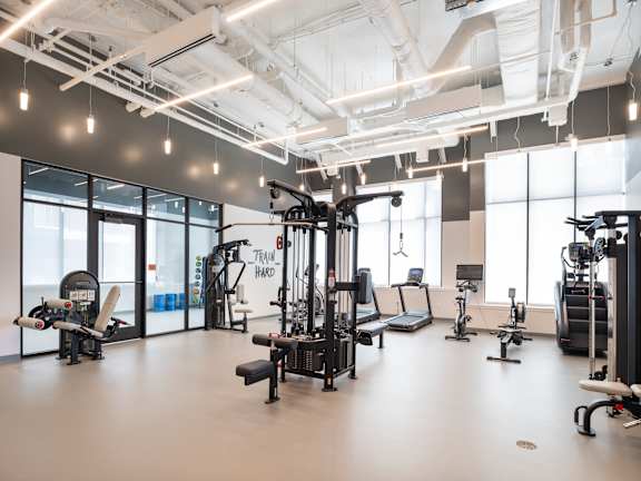 A gym with a variety of equipment including a treadmill, weights, and a stationary bike.