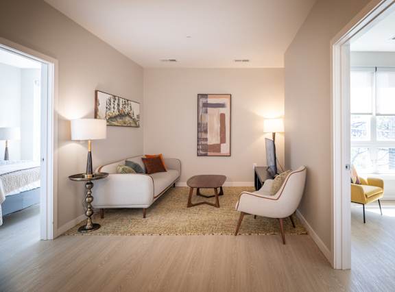 A living room with a white couch, a yellow chair, and a painting on the wall.