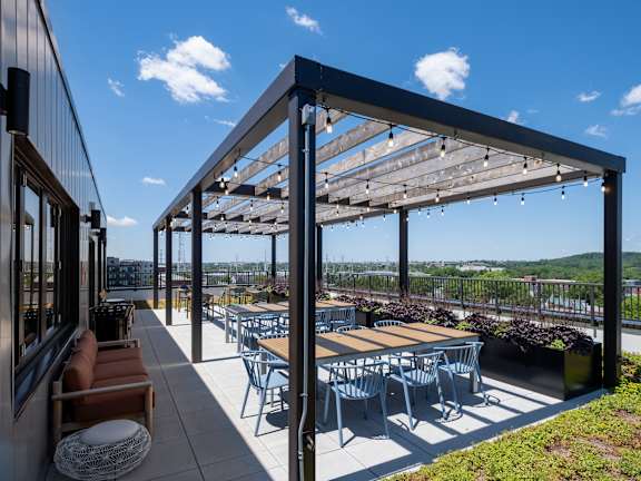 A patio with tables and chairs under a pergola.