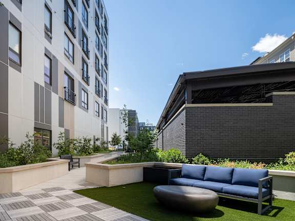 A modern outdoor seating area with a blue sofa and a circular table.