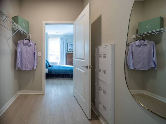 A hallway with a bedroom at the end and two shirts hanging up at Jayde Parkside Apartments, Washington, DC, 20019