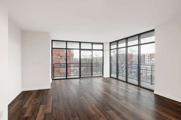 A room with wooden floors and large windows overlooking a cityscape.