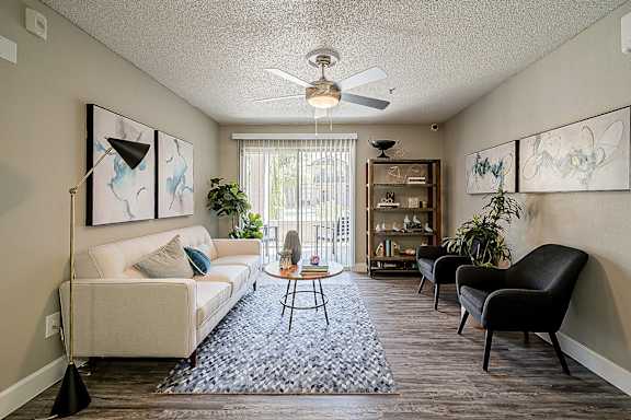 A living room with a white couch, a coffee table, and a ceiling fan at Sterling Point Apartment Homes, Arizona