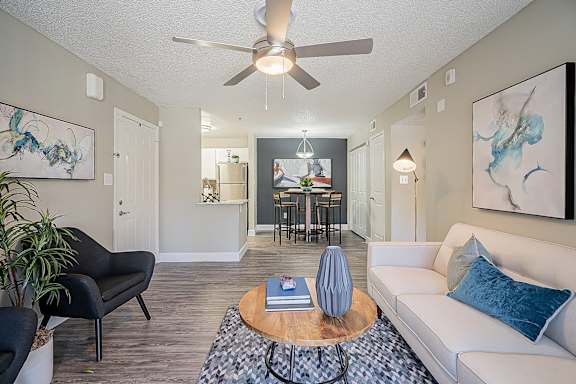 A living room with a black chair, a white couch, and a wooden coffee table at Sterling Point Apartment Homes, Arizona, 85042