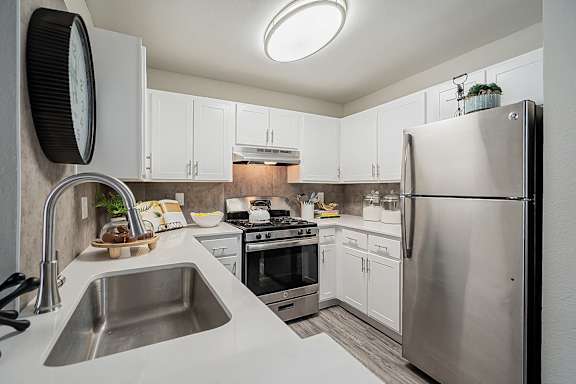 A modern kitchen with a stainless steel refrigerator and a sink with a faucet at Sterling Point Apartment Homes, Phoenix, Arizona