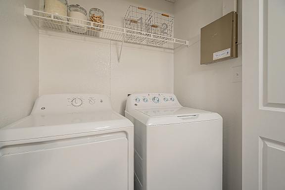 Two white front loading washing machines in a small laundry room at Sterling Point Apartment Homes, Phoenix, Arizona