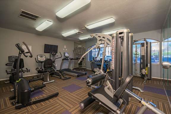 A gym with a variety of equipment including treadmills, stationary bikes, and weight machines at Sterling Point Apartment Homes, Phoenix
