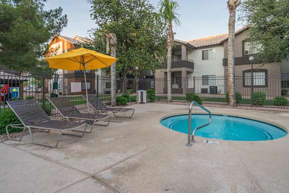 A pool area with a yellow umbrella and lounge chairs at Sterling Point Apartment Homes, Phoenix, Arizona