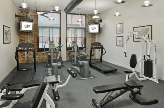 a gym with weights and exercise equipment in a room with windows at Tindeco Wharf, Baltimore