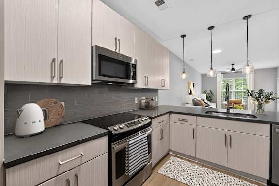 A modern kitchen with a black countertop and white cabinets.