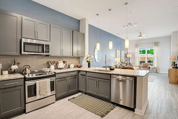 A modern kitchen with dark grey cabinets and stainless steel appliances.