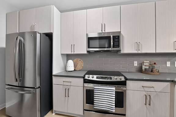 A modern kitchen with a stainless steel refrigerator, microwave, and oven.