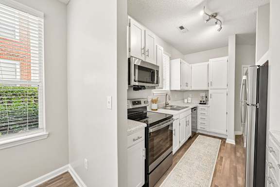 A kitchen with white cabinets and appliances.