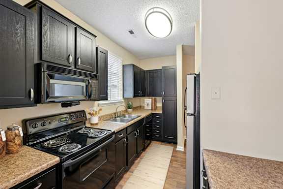 A kitchen with black cabinets and a black stove top oven.