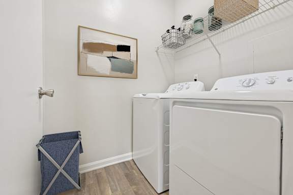 A laundry room with a washer and dryer and a painting on the wall.