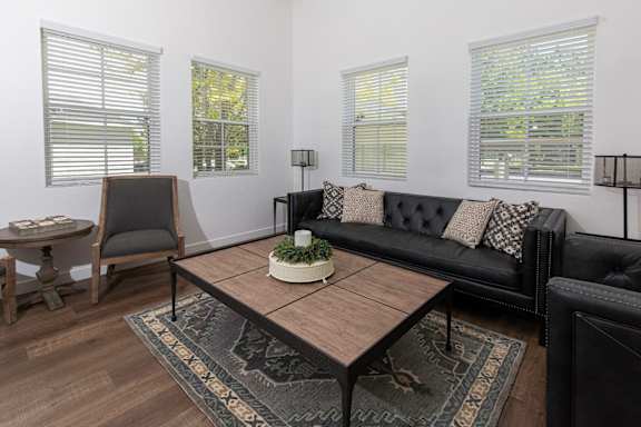 A black couch with a coffee table in front of it. at Bluffs Apartments, Bluffdale