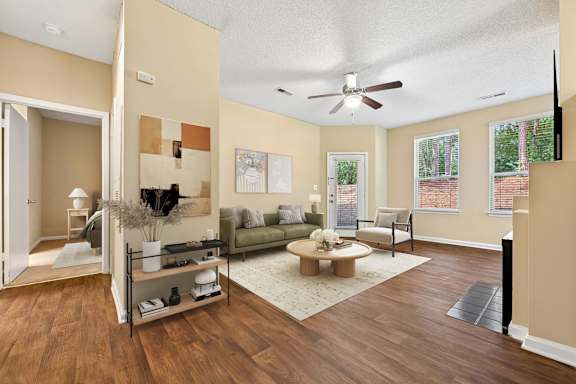 A living room with a brown floor and a ceiling fan.