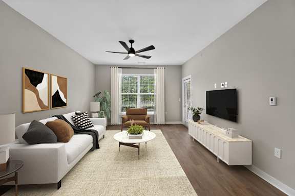 A living room with a white couch, a coffee table, and a television.