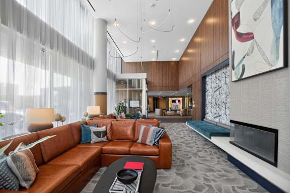A modern living room with a brown leather couch and a fireplace.