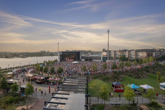 a large crowd is gathered in front of a large stage near a body of water at Metropolitan at the Riverwalk, North Carolina, 28401