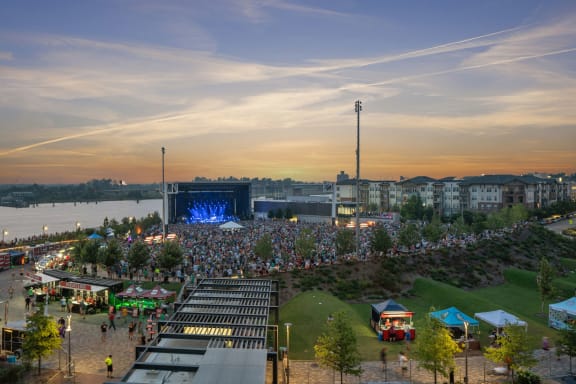 a crowd of people in front of a stage at dusk at Metropolitan at the Riverwalk, Wilmington North Carolina