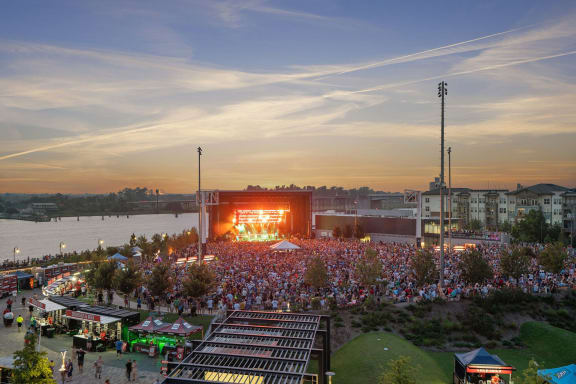 a crowd of people in front of a stage with a sunset in the background at Metropolitan at the Riverwalk, Wilmington