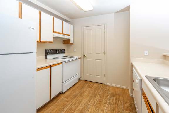 A kitchen with white appliances and wooden floors.at Sunset Ridge, West Jordan, 84081